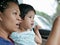 Little Asian baby girl having fun traveling with her mother by car as she learning to tell what she see during the trip