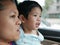 Little Asian baby girl having fun traveling with her mother by car as she learning to tell what she see during the trip