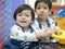 Little Asian baby girl left enjoys playing arcade game with her older sister