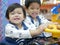 Little Asian baby girl left enjoys playing arcade game with her older sister