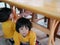 Little Asian baby girl sitting and playing / exploring with her younger sister under a dinning table at a restaurant - toddler