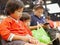 Little Asian baby girl, together with her younger sister, watching a smartphone, same as her mom, sitting and waiting for a queue