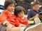 Little Asian baby girl, together with her younger sister, watching a smartphone, same as her mom, sitting and waiting for a queue