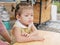 Little Asian baby girl waiting for food at a dinning table