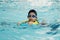 Little asian boy learn swimming in pool and swim using foampad
