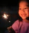 Little Asian child girl enjoy playing firecrackers. Focus at fire sparklers