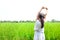 Little Asian child girl feel relax and fresh in young green rice field. Rear view. Freedom and relax concept