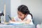 Little Asian girl doing homework with concentration, select focus