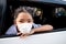 The little Asian girl wears a hygiene mask in a car
