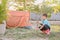 Little Asian kid having fun holding hammer, pretend to set up a camping tent in backyard at home
