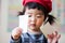 A little asian kid with red long hat looking at papers