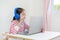 Little asian school girl using headphone study online learning class by video call on laptop computer with teacher during new