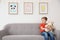 Little autistic boy sitting on sofa with toy