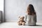 Little autistic girl with teddy bear sitting on floor at empty room. Autism concept