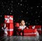 Little baby babe with santa costume with red boxes on a dark background