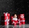 Little baby babe with santa costume with red boxes on a dark background