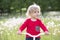 Little baby on a bicycle on a green meadow.