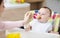 Little baby boy eating healthy breakfast, sitting in high chair