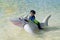 A Little baby boy with inflatable toy float playing in the water on summer vacation in a tropical resort. Kid with toy shark on a