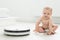 Little baby boy looks at the robotic vacuum cleaner at home.