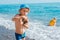 Little baby boy playing on the beach by the sea in sand and stones. Build sand castles.