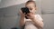 Little baby boy sits on the bed and plays with a smartphone. The baby's holding a black cell phone. Close-up, slow