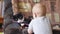 Little baby boy is teasing and playing with black white cat that lying on his back on a sofa. People and animals concept