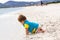 Little baby boy wearing blue rash guard suit playing on tropical ocean beach. UV and sun protection for young children. Toddler ki