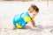 Little baby boy wearing blue rash guard suit playing on tropical ocean beach. UV and sun protection for young children. Toddler ki