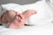 Little baby with cute feet lying on bed. Space for text