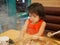 Little baby girl is addicted to a smartphone, keeps watching video streaming, while ignoring the meal in front of her