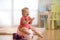 Little baby girl claps sitting on chamberpot in nursery room