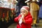 Little baby girl, cute child eating bananas covered with chocolate, marshmellows and colorful sprinkles near sweet stand