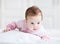 Little baby girl enjoying tummy time in a pink cardigan