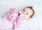 Little baby girl enjoying tummy time in a pink cardigan