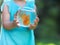 Little baby girl holding a fishbowl with a goldfish on a nature