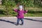 Little baby girl in jeans jacket and hat making learning to walk his first steps on the lawn in the green grass