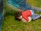 Little baby girl lying on a dinosour egg, pretending she is a dinosour mother, and hoping the egg will hatch soon