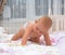 Little baby girl in a nappy crawling on a bed.