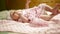 Little baby girl in a pink dress lies on a bed