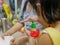 Little baby girl`s hand pressing on the cap of a dishwashing liquid bottle, while helping her mother clean dishes at home