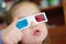 Little baby girl showing super in 3D anaglyph cinema glasses for stereo image system with polarization. 3D goggles with red and bl