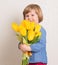 Little baby girl siting on the floor in bright room plays with cat and tulip flowers. Happy child playing at home