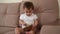 Little baby girl sitting on the couch and playing a musical instrument Kalimba