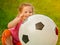 Little baby girl sitting with a huge ball of football colors.