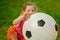 Little baby girl sitting with a huge ball of football colors.