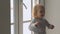 Little baby girl standing near the window and emotionally gesticulates