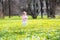 Little baby girl walking among yellow flowers