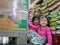 Little baby girls, sisters, playing / hiding behind a big boxes of instant noodles at a supermarket - hide and seek