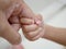 Little baby hand holding father`s finger representing father-and-child love, intimacy, and assistance